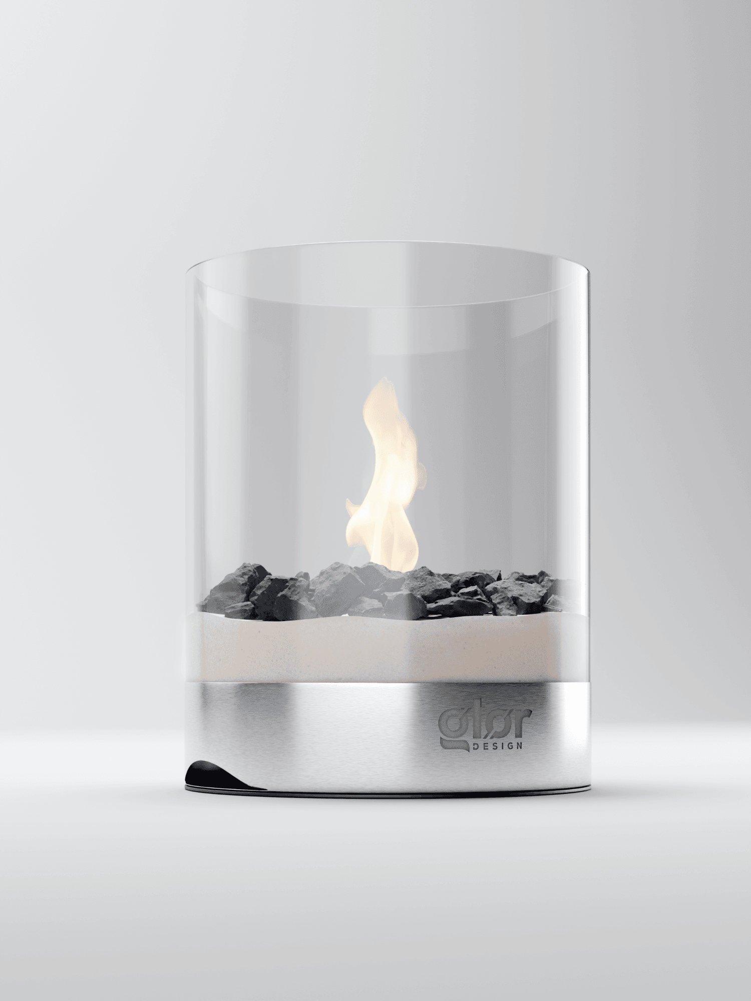 A modern tabletop fireplace with a cylindrical glass enclosure, black stones, and a stainless steel base featuring theQFLAME" logo, displaying a small, clean-burning flame.