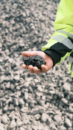 A handful of raw Larvikite stones with their blue shimmer, held above the quarry floor