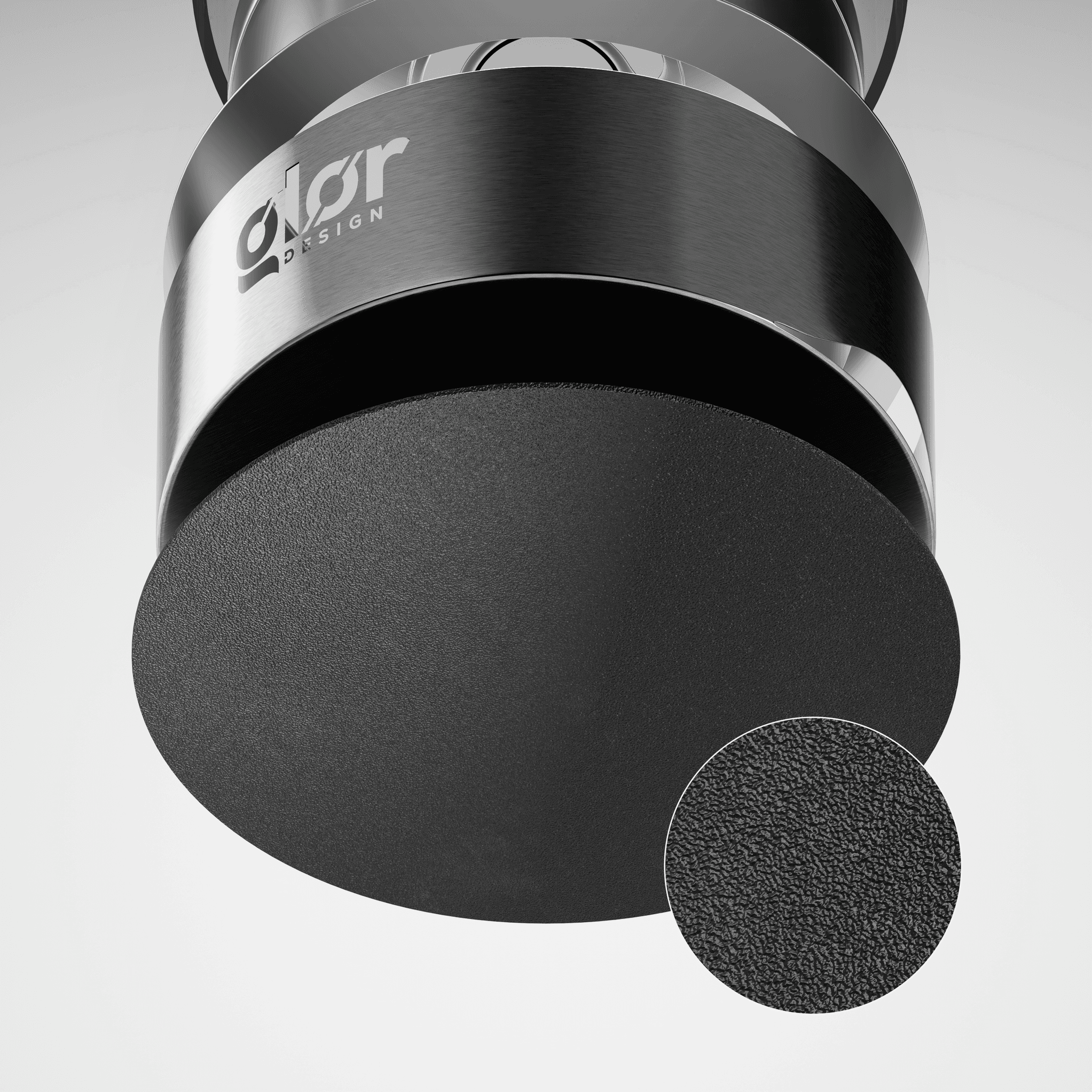 Close-up view of a modern black and silver cylindrical object with a textured matte black surface, featuring theØlor Design" logo and a magnified inset showing the fine surface texture.